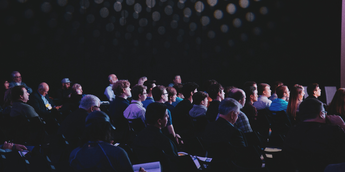 Publikum im abgedunkelten Saal bei einem Kongress in Stuttgart
